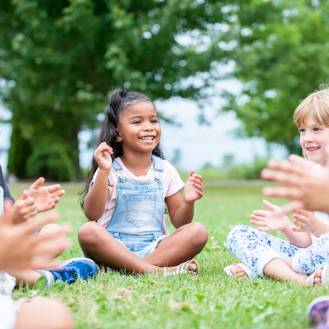 Little girl enjoying clapping in a circle with friends